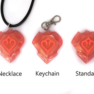 May include: Three versions of a pink and orange resin pendant with a stylized heart design. The pendant is available as a necklace, keychain, or standard.