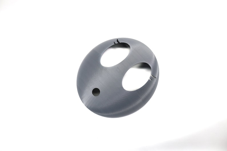 May include: A gray plastic 3D printed object with two oval-shaped cutouts and a small round hole in the center.