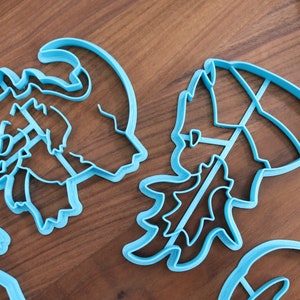 May include: Four blue plastic cookie cutters shaped like a reindeer, a Christmas tree, a snowman, and a Santa Claus hat.