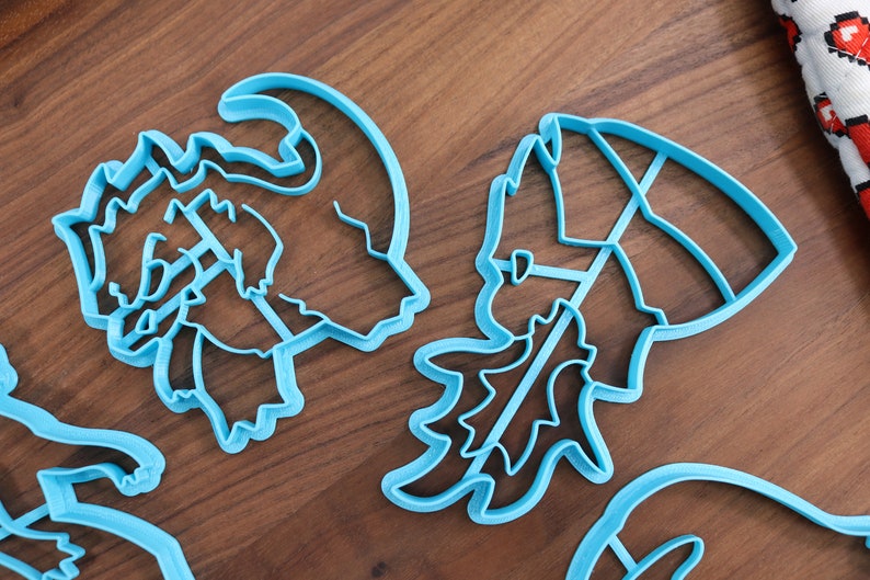 May include: Four blue plastic cookie cutters shaped like a reindeer, a Christmas tree, a snowman, and a Santa Claus hat.
