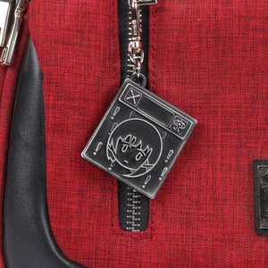 May include: Red zippered bag with a black metal zipper pull featuring a cartoon character with a surprised expression. The bag has a black leather trim and a black patch with the text "Where is the Where to Resolve Goods Where" and the logo "TOKYOBANANAN".