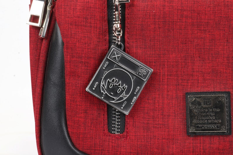 May include: Red zippered bag with a black metal zipper pull featuring a cartoon character with a surprised expression. The bag has a black leather trim and a black patch with the text "Where is the Where to Resolve Goods Where" and the logo "TOKYOBANANAN".