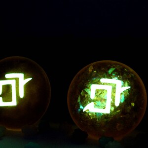 May include: Two glowing yellow orbs with a white symbol inside. The symbol is a stylized "J" with a small line extending from the top.