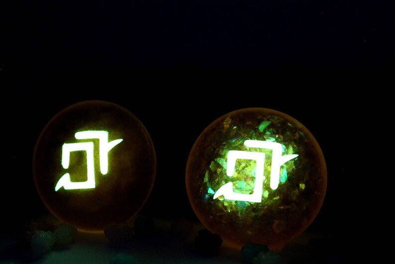 May include: Two glowing yellow orbs with a white symbol inside. The symbol is a stylized "J" with a small line extending from the top.