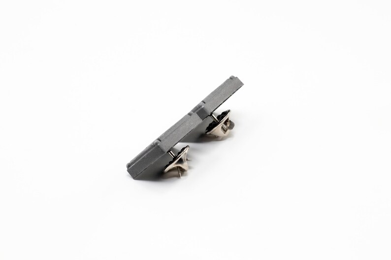 Peut inclure: Un bouton de pin en m&eacute;tal gris avec deux attaches en m&eacute;tal.