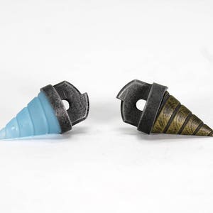 May include: Two drill bit shaped charms, one is blue and the other is gold. Both have a silver metal ring.