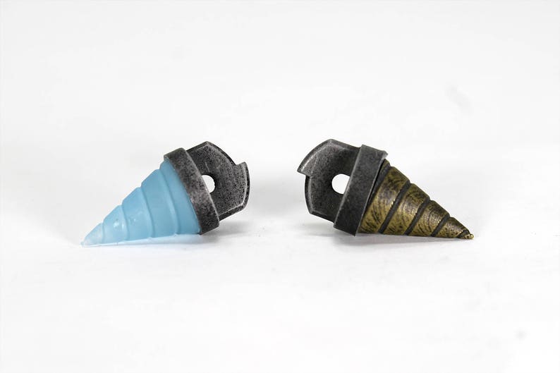 May include: Two drill bit shaped charms, one is blue and the other is gold. Both have a silver metal ring.