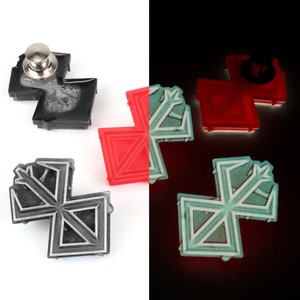 May include: Four black and silver pins with a geometric design. The pins are in the shape of a cross with a pointed tip at the top. The pins are on a white background. One pin has a silver pin back.