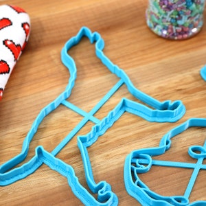 Peut inclure: Trois emportes-pi&egrave;ces en plastique bleu en forme de chien, d'os et de bol. Les emportes-pi&egrave;ces sont sur une surface en bois.