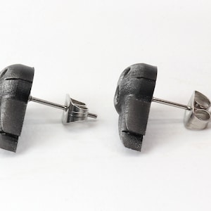 Peut inclure: Une paire de boucles d'oreilles en argent avec un motif de cr&acirc;ne 3D textur&eacute; noir.