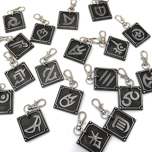 May include: A set of 18 silver-colored metal keychains with different symbols on each. The keychains are square-shaped and have a silver-colored metal ring.
