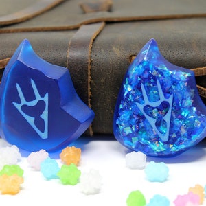 May include: Two blue resin dice with a white paw print design. One die has a glittery finish.