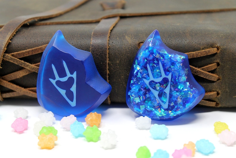 May include: Two blue resin dice with a white paw print design. One die has a glittery finish.