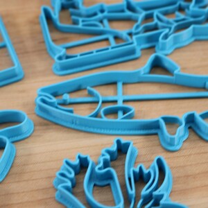 May include: A set of blue plastic cookie cutters in various shapes, including a fish, a star, a flower, and a Christmas tree.