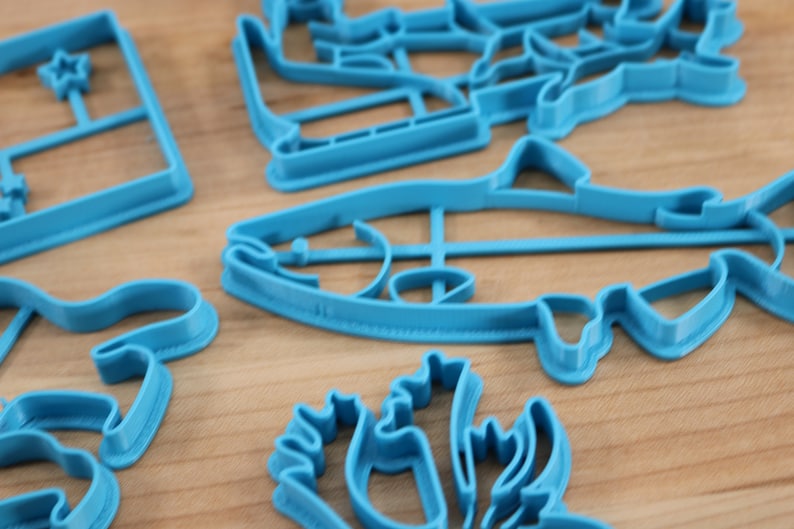 May include: A set of blue plastic cookie cutters in various shapes, including a fish, a star, a flower, and a Christmas tree.