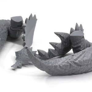 May include: Gray plastic model of a monster's tail with sharp claws and textured skin.