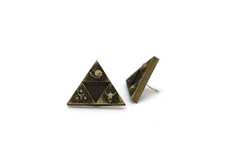 May include: A pair of gold-toned earrings featuring a triangular design with a stylized image of a triforce. The triforce is a symbol from the Legend of Zelda video game series.