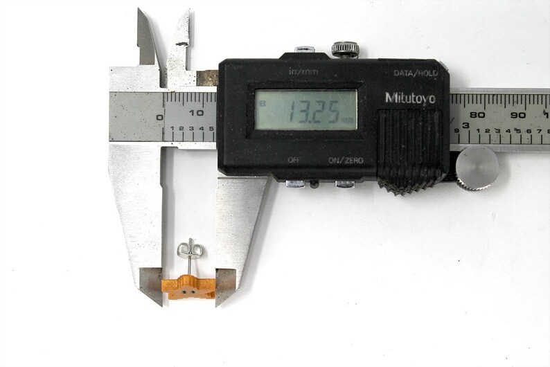 May include: A close-up of a digital caliper measuring a small wooden object. The caliper reads 13.25 mm.