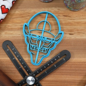 May include: A blue plastic cookie cutter shaped like a cartoon character with a hat and a large nose.