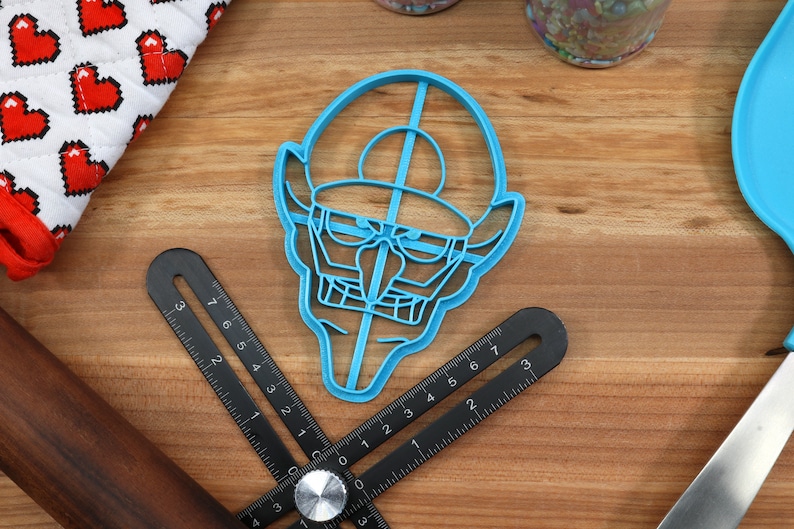 May include: A blue plastic cookie cutter shaped like a cartoon character with a hat and a large nose.
