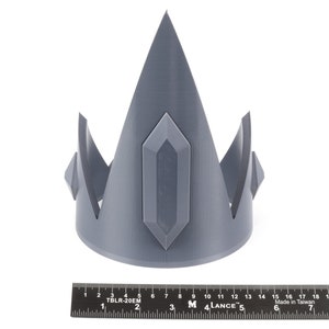 May include: A gray 3D printed crown with a pointed top and a large, rectangular gem in the center.