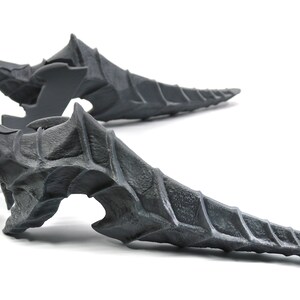 May include: Two grey, 3D printed, dragon tail-like sculptures with a spiky, textured surface.