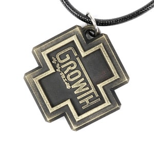 May include: A black metal pendant with a gold cross design and the word "GROWITH" inscribed on it. The pendant is attached to a black cord.