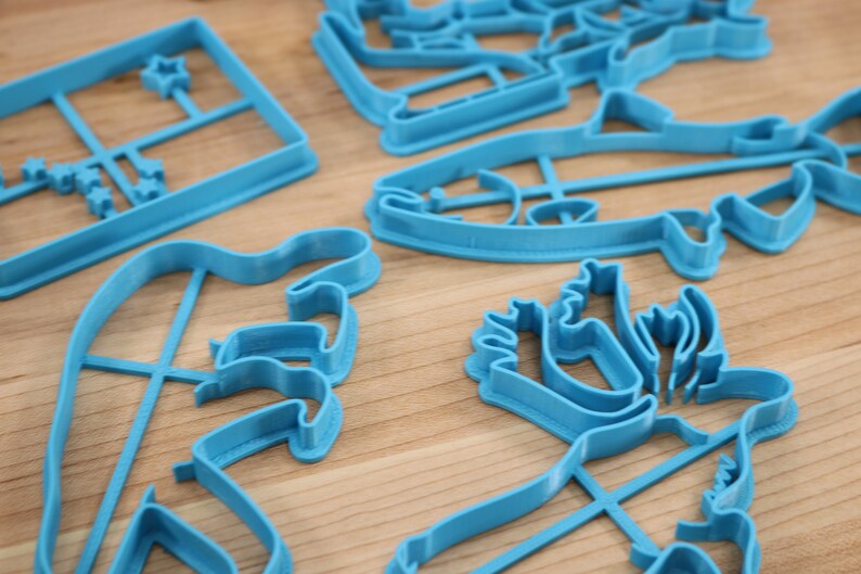 May include: A set of blue plastic cookie cutters in various shapes, including a fish, a reindeer, a star, and a geometric design.