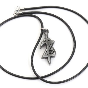 May include: A black cord necklace with a silver pendant featuring a stylized sword and the letter Z.