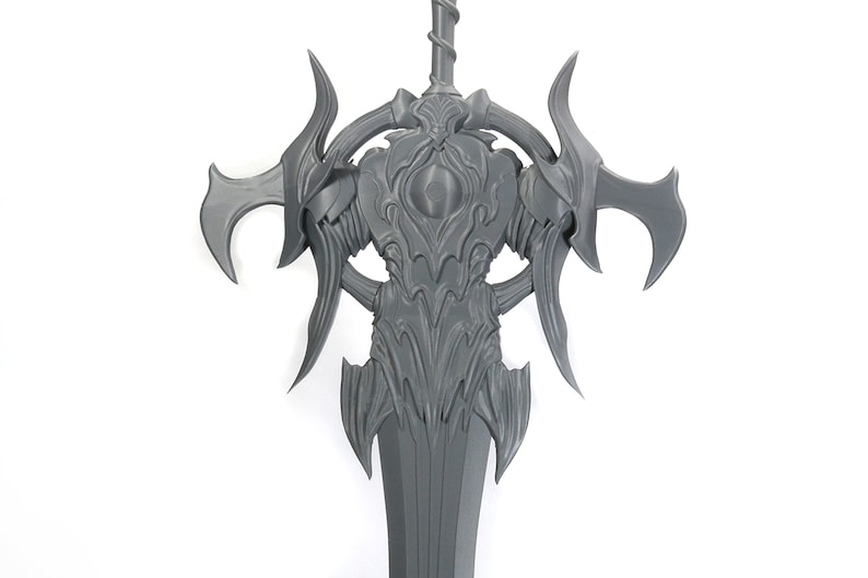 May include: A gray 3D printed sword with intricate details and a large, ornate hilt. The sword has a sharp point and a double-edged blade.