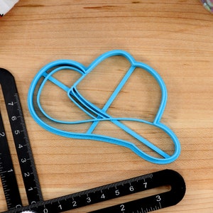 May include: A light blue plastic cookie cutter shaped like a cowboy hat.