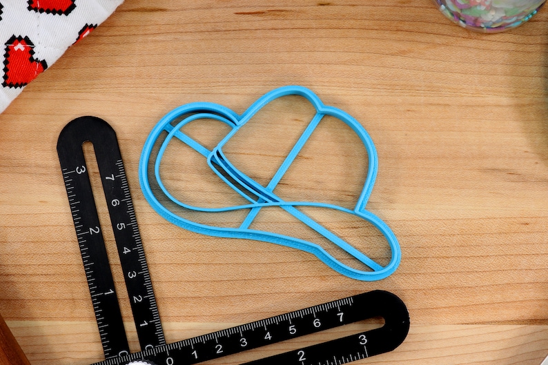 May include: A light blue plastic cookie cutter shaped like a cowboy hat.
