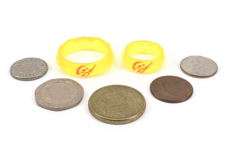 May include: Two yellow silicone rings with a red logo, surrounded by six coins of different sizes and colors.