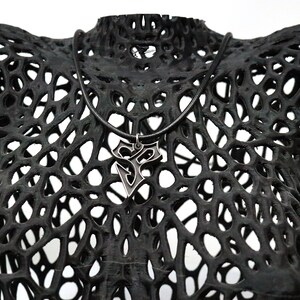 May include: A black, 3D printed, geometric, lattice-like sculpture with a silver pendant necklace hanging from it.