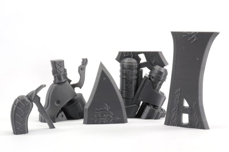 May include: A set of gray 3D printed plastic pieces for a model kit. The pieces include a figure, a weapon, and a shield.