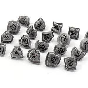 May include: A set of 18 silver-colored metal dice with black symbols. The dice are in various shapes and sizes, and each has a different symbol on it.
