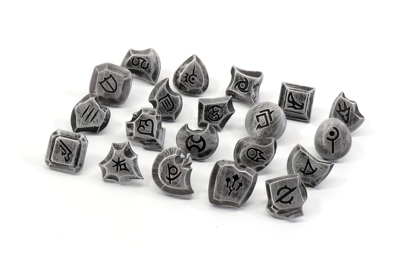 May include: A set of 18 silver-colored metal dice with black symbols. The dice are in various shapes and sizes, and each has a different symbol on it.