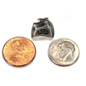 May include: A silver metal dice with the number 8 engraved on it. The dice is shown next to a US penny and a US dime for size comparison.