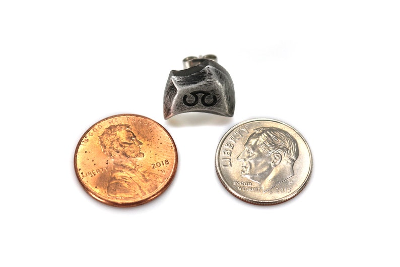 May include: A silver metal dice with the number 8 engraved on it. The dice is shown next to a US penny and a US dime for size comparison.