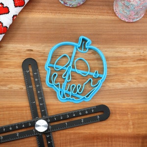 May include: A blue plastic cookie cutter shaped like a poisoned apple with a skull and crossbones design.