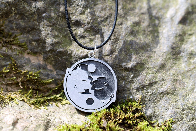 May include: A silver necklace with a yin yang pendant featuring a black and white design of two stylized faces.