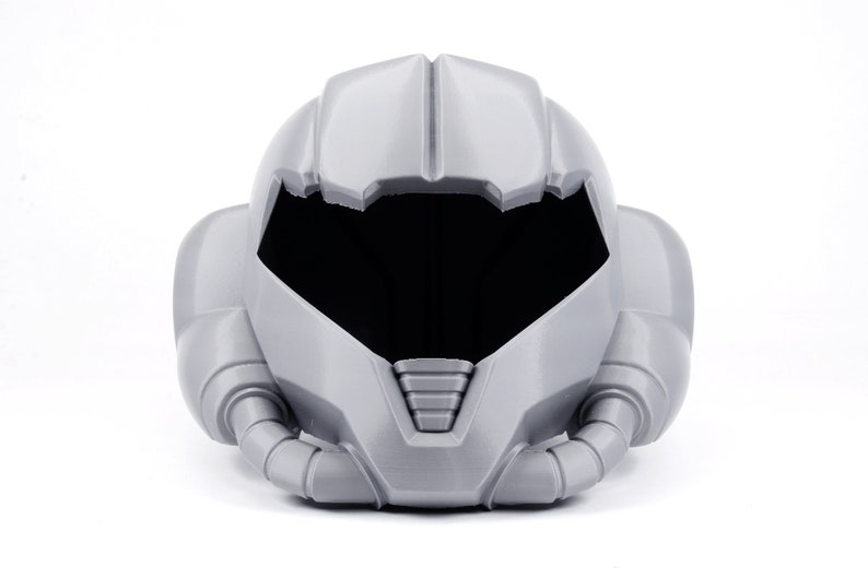 May include: A gray plastic helmet with a visor and a detailed design. The helmet has a futuristic look and is reminiscent of a space suit.