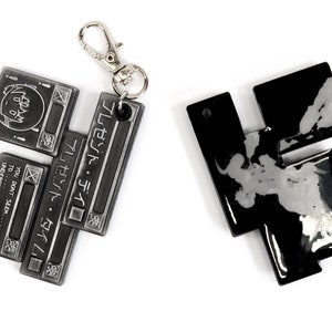 May include: Two metal keychains, one silver and one black, with a geometric design. The silver keychain has the text "プレゼント・タイム" and "YOU DON'T SEEM... TO... UNDERSTAND... A SHAME" on it.