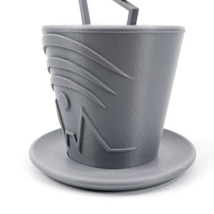 Pode incluir: Um chap&eacute;u cinza impresso em 3D com um design geom&eacute;trico e um pires correspondente. O chap&eacute;u tem um design em relevo na frente.