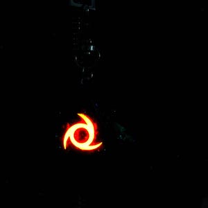 Pu&ograve; includere: Un portachiavi nero con un simbolo arancione e rosso luminoso. Il simbolo &egrave; un vortice stilizzato con tre punti.