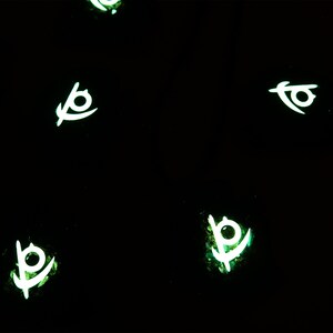 May include: Five glowing green and white symbols on a black background. The symbols are stylized eyes with a curved line extending from the bottom.