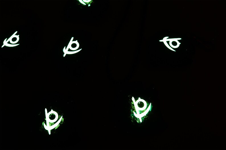 May include: Five glowing green and white symbols on a black background. The symbols are stylized eyes with a curved line extending from the bottom.