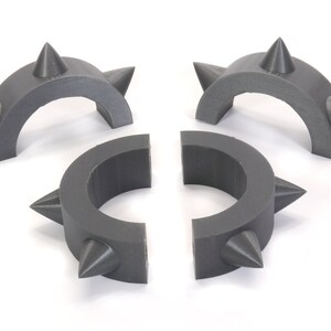 May include: Four grey plastic spiked rings, two are half circles and two are full circles.