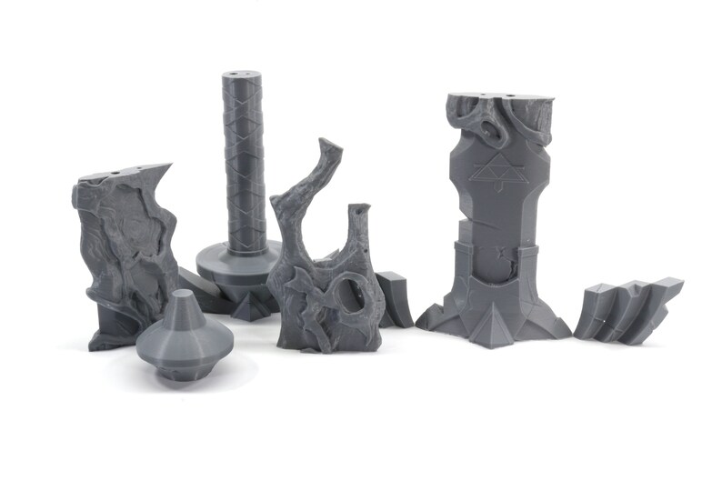 May include: A set of six gray 3D printed miniature dungeon pieces, including a pillar, a tree stump, a wall, and a broken wall.