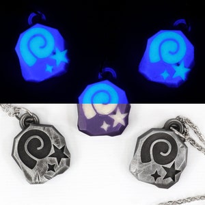 May include: Three silver necklaces with a glow-in-the-dark charm featuring a spiral and stars. The charms are in the shape of a rock.